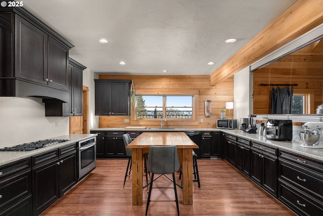 kitchen with sink, dark wood-type flooring, stainless steel appliances, wood walls, and wood counters