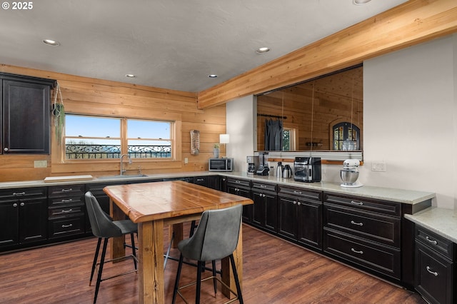 kitchen with dark hardwood / wood-style flooring, sink, wood walls, kitchen peninsula, and beam ceiling