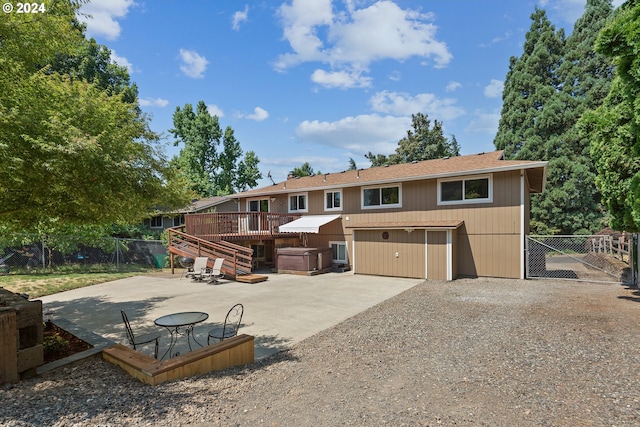 rear view of house featuring a wooden deck, a patio, and a hot tub