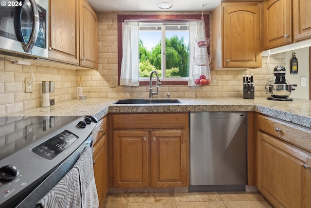 kitchen featuring stainless steel appliances, light tile patterned floors, sink, and backsplash