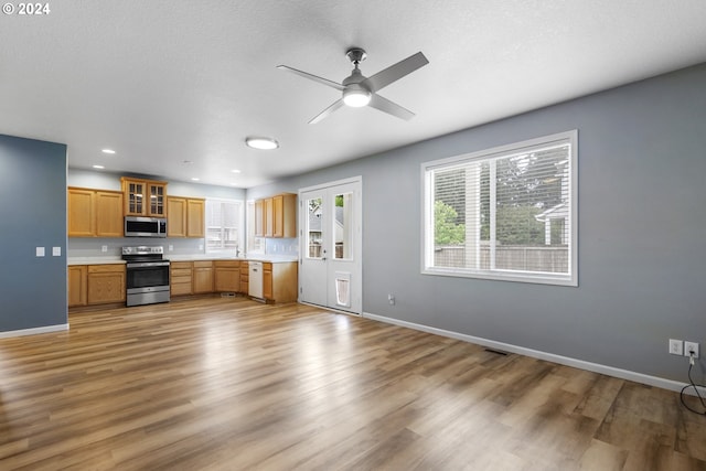 kitchen with ceiling fan, sink, stainless steel appliances, and light wood-type flooring