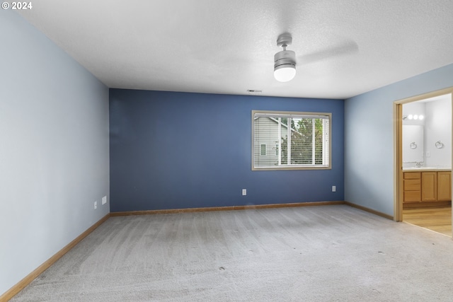 interior space with ensuite bathroom, ceiling fan, sink, and light carpet