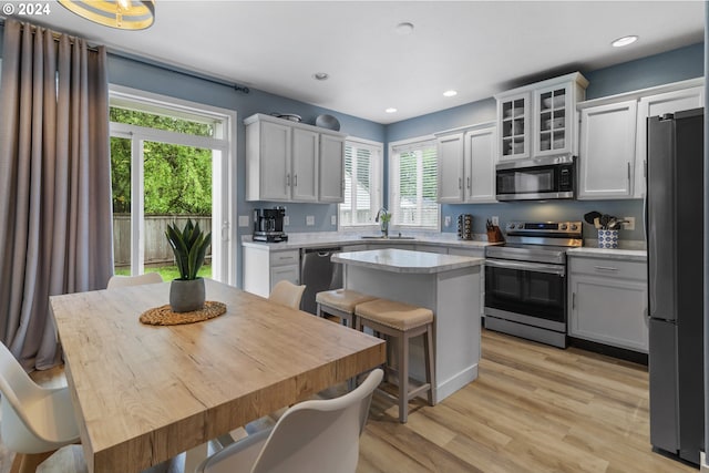 kitchen with a breakfast bar, light hardwood / wood-style flooring, appliances with stainless steel finishes, a kitchen island, and white cabinetry