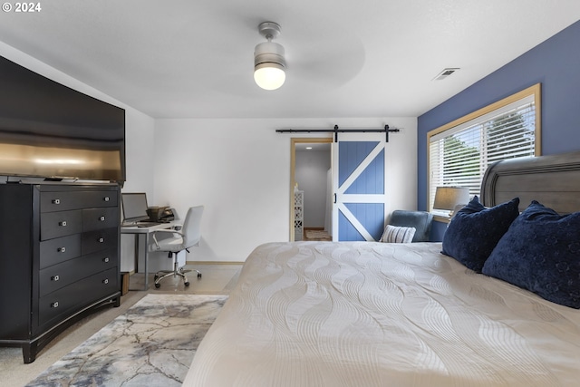 bedroom featuring ceiling fan, a barn door, and light carpet