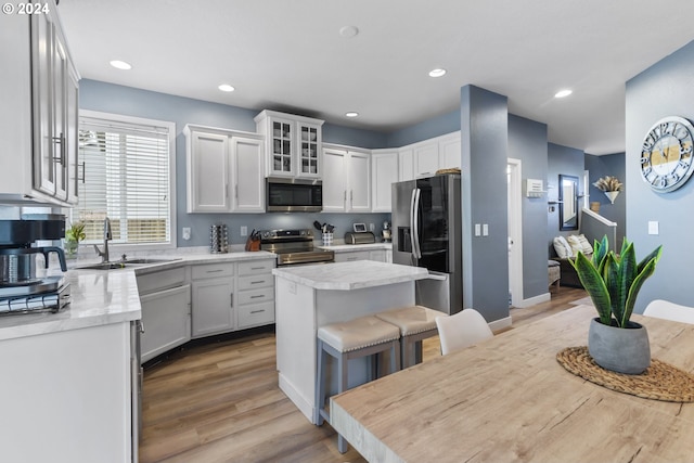 kitchen featuring white cabinets, sink, a kitchen island, a kitchen bar, and stainless steel appliances