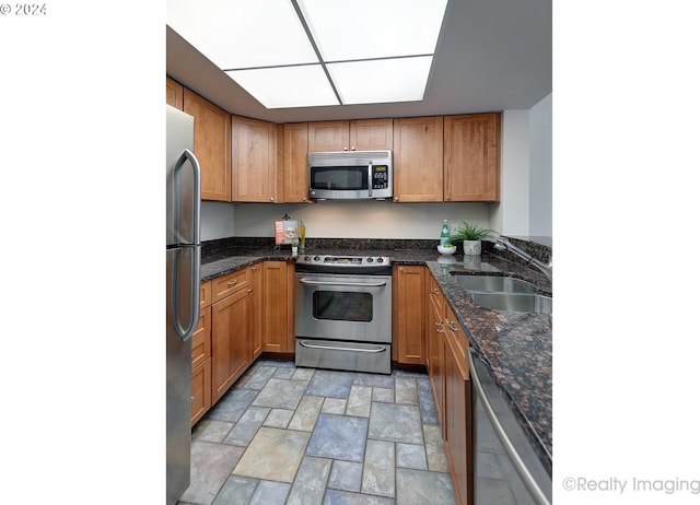 kitchen with dark stone countertops, stainless steel appliances, and sink