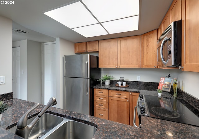 kitchen featuring dark stone countertops, appliances with stainless steel finishes, and sink