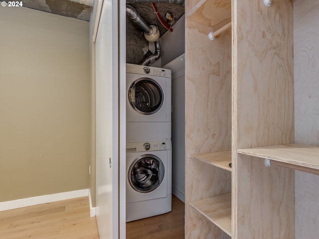 washroom featuring hardwood / wood-style flooring and stacked washer / dryer