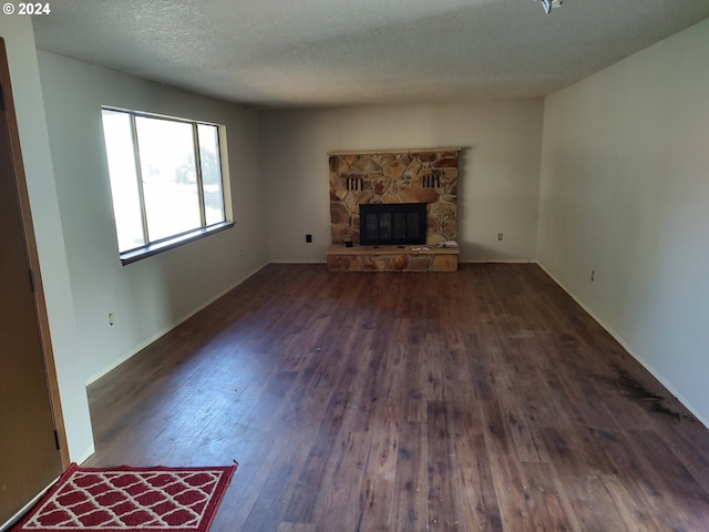 unfurnished living room with dark wood-type flooring, a textured ceiling, and a fireplace