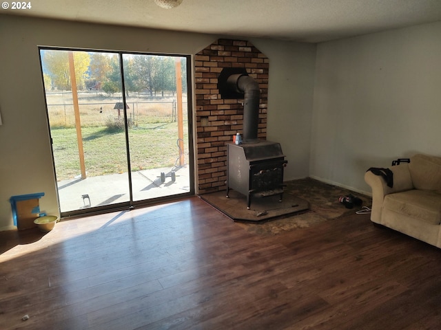 unfurnished living room with a textured ceiling, a wood stove, and wood-type flooring