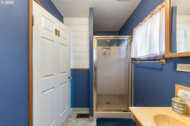 bathroom featuring wood walls, a shower with door, and vanity