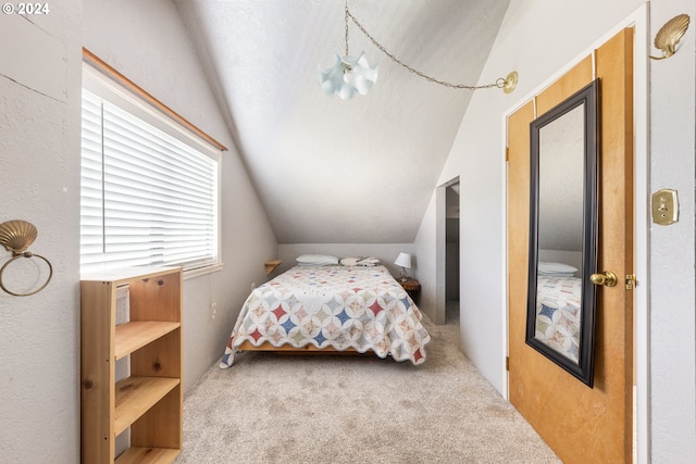 bedroom featuring a chandelier, lofted ceiling, a textured ceiling, and carpet floors