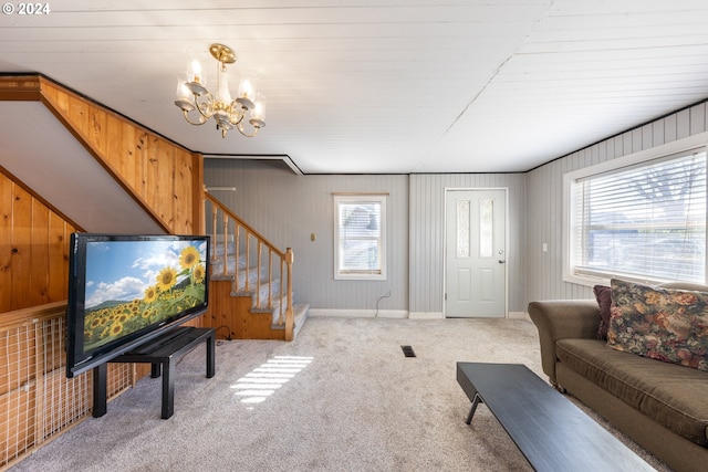 carpeted living room with a chandelier, a wealth of natural light, and wooden walls