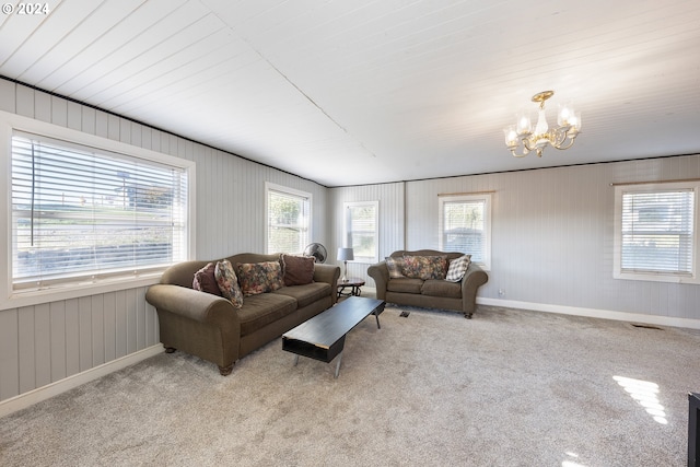 carpeted living room with a notable chandelier, a healthy amount of sunlight, and wooden walls