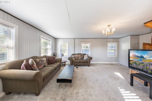 carpeted living room with wood walls, plenty of natural light, and a notable chandelier