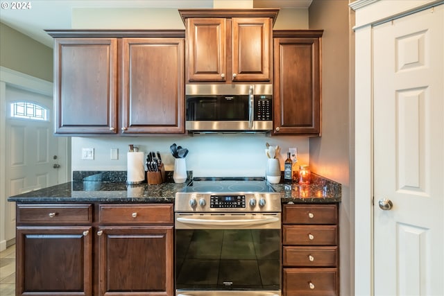 kitchen with tile patterned floors, dark stone counters, and appliances with stainless steel finishes