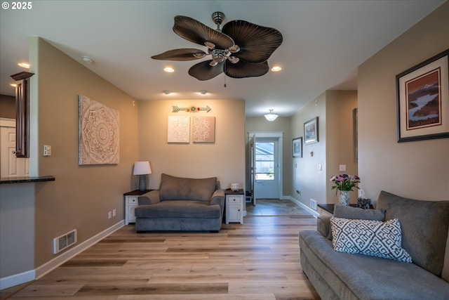 living room featuring baseboards, visible vents, light wood-type flooring, and a ceiling fan