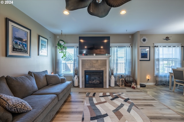 living room featuring a fireplace, light wood-type flooring, and ceiling fan