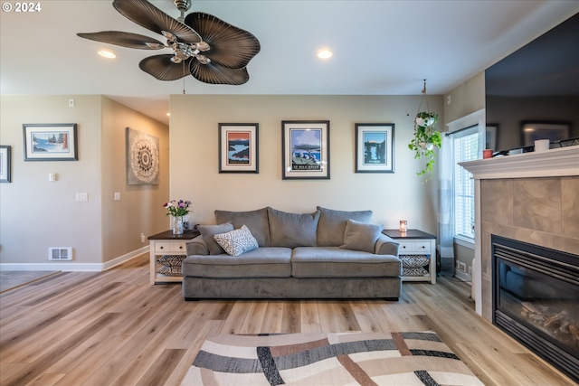 living room with a fireplace, light hardwood / wood-style flooring, and ceiling fan