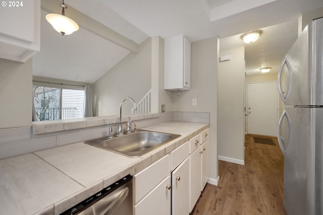 kitchen with stainless steel appliances, white cabinetry, hanging light fixtures, and sink