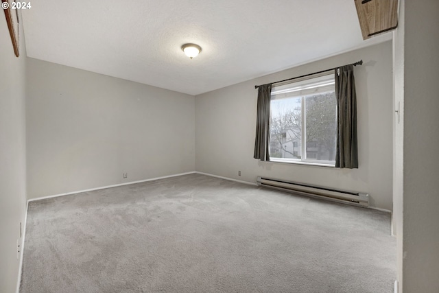 spare room with a textured ceiling, light colored carpet, and a baseboard heating unit