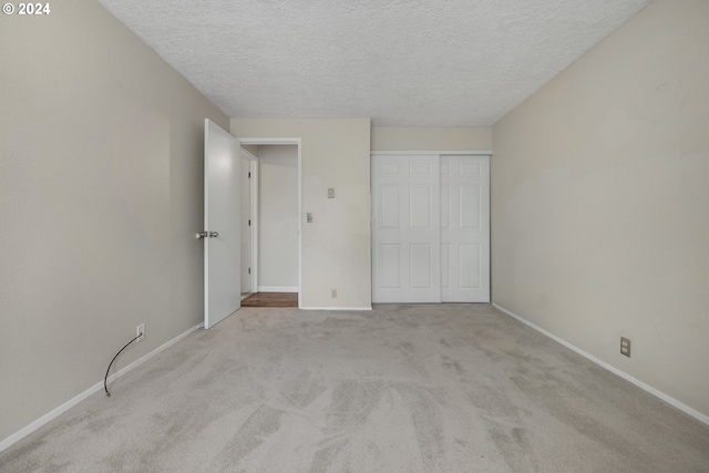 unfurnished bedroom with light carpet, a textured ceiling, and a closet