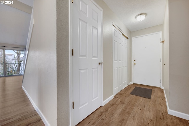 hall featuring light hardwood / wood-style floors and a textured ceiling