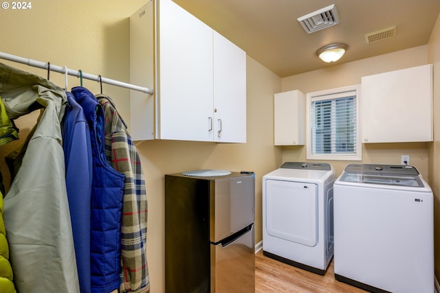 washroom featuring cabinets, light hardwood / wood-style flooring, and washer and clothes dryer