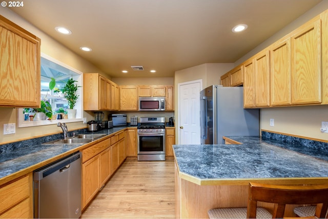 kitchen with a kitchen breakfast bar, sink, light hardwood / wood-style floors, kitchen peninsula, and stainless steel appliances