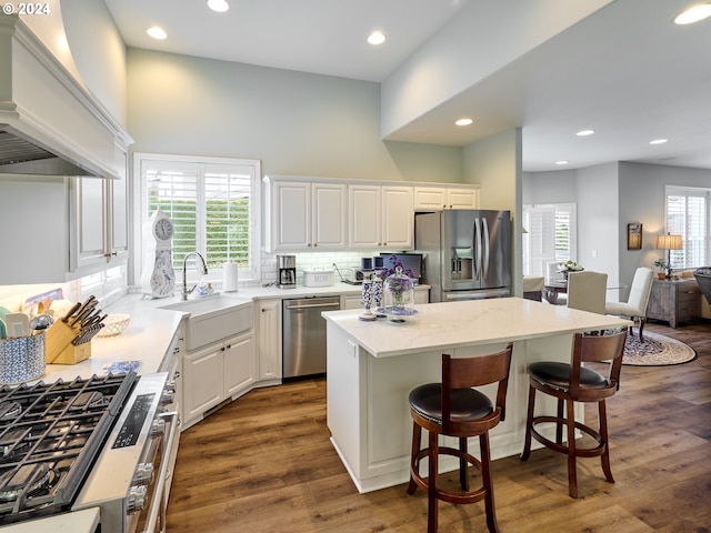 kitchen featuring sink, custom exhaust hood, a center island, stainless steel appliances, and white cabinets