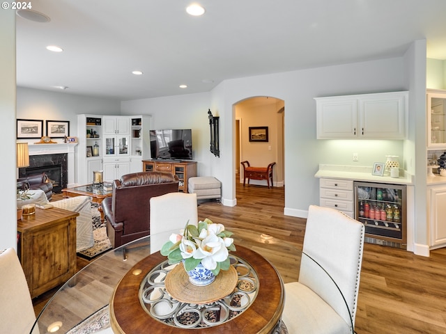 dining room with wine cooler, bar area, a premium fireplace, and light wood-type flooring