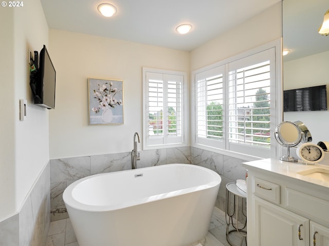 bathroom featuring tile walls, vanity, and a bathing tub