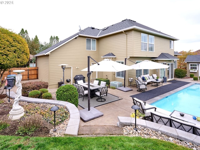 rear view of property with a fenced in pool, outdoor lounge area, and a patio area