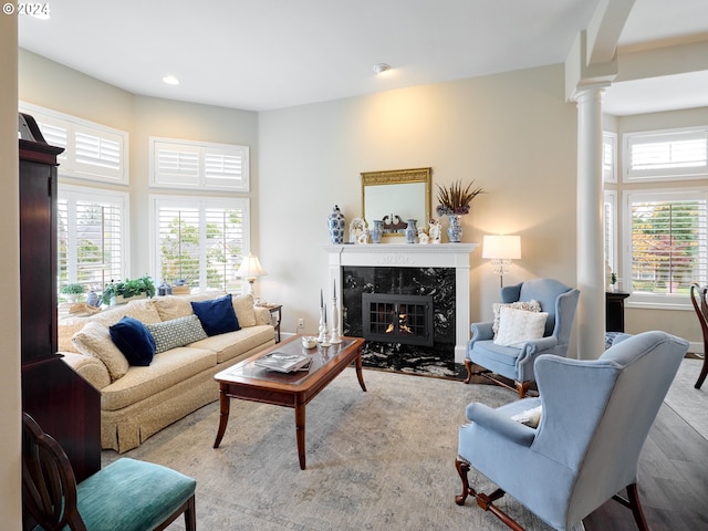 living room featuring decorative columns, light wood-type flooring, and a fireplace