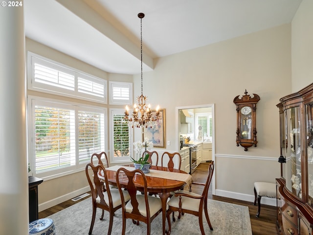 dining space with a high ceiling, plenty of natural light, dark hardwood / wood-style floors, and an inviting chandelier