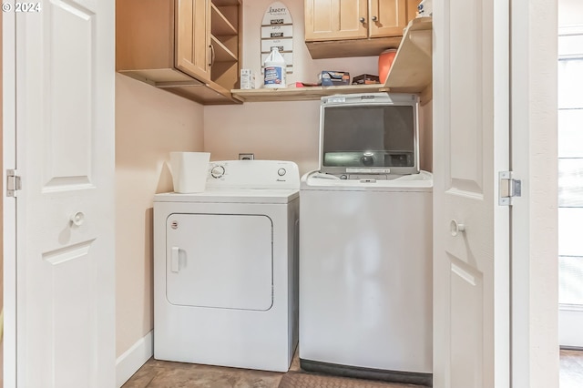 clothes washing area featuring cabinets, independent washer and dryer, and a wealth of natural light