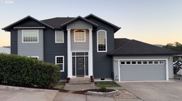 view of front facade with driveway, a shingled roof, and a garage