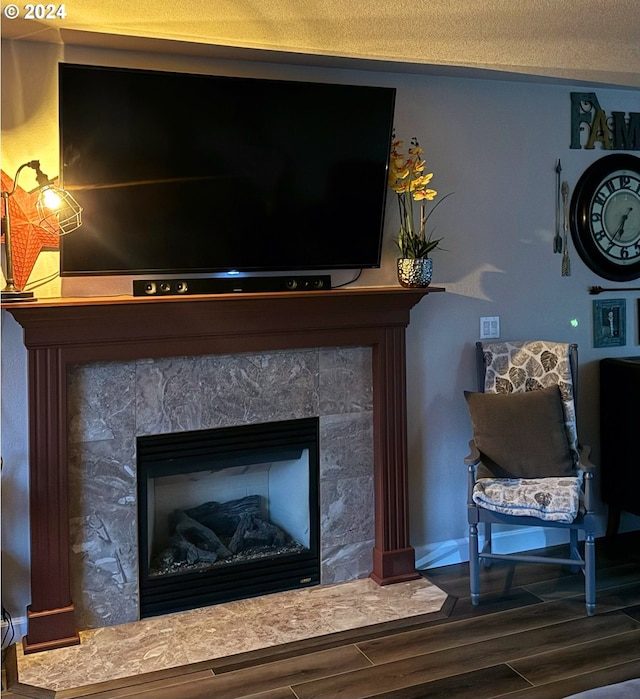 room details featuring a textured ceiling, a tiled fireplace, and hardwood / wood-style floors