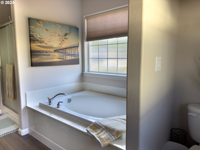 bathroom featuring wood-type flooring, toilet, and shower with separate bathtub