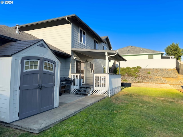 rear view of property featuring a storage unit and a lawn