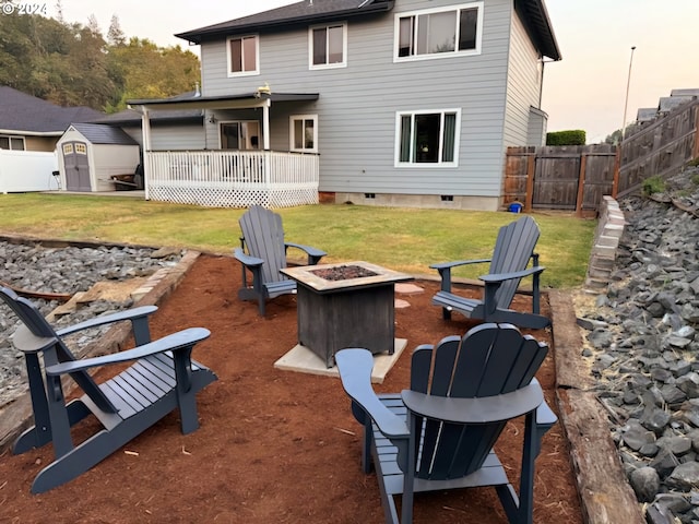 back house at dusk with a fire pit, a storage shed, and a wooden deck