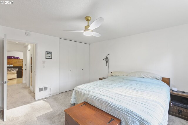 bedroom featuring ceiling fan, a closet, and light colored carpet