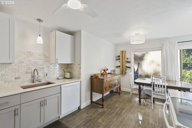 kitchen with decorative backsplash, sink, dishwasher, dark hardwood / wood-style floors, and hanging light fixtures