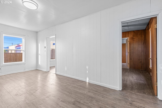 unfurnished room featuring wooden walls and hardwood / wood-style floors