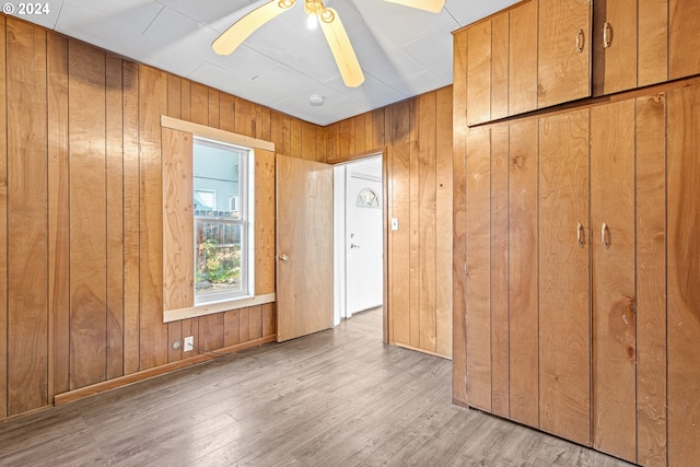 interior space featuring wood walls, ceiling fan, and light hardwood / wood-style floors