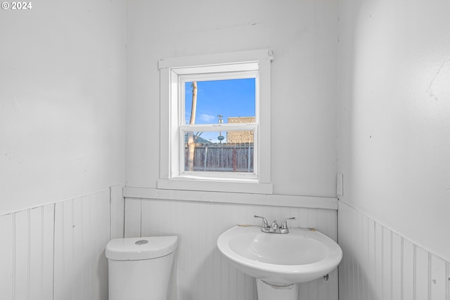 bathroom featuring wood walls, sink, and toilet