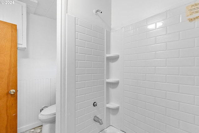 bathroom with tiled shower / bath combo and toilet