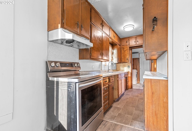 kitchen with stainless steel electric range oven, sink, and washer / clothes dryer