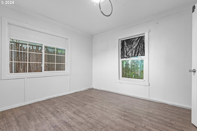 spare room featuring a healthy amount of sunlight, ornamental molding, and hardwood / wood-style floors