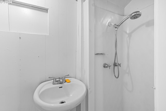 bathroom with a shower, sink, and wooden walls